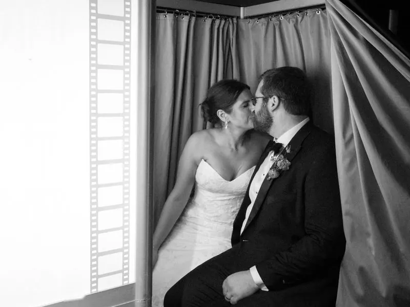 Wedding couple kissing inside an enclosed photo booth