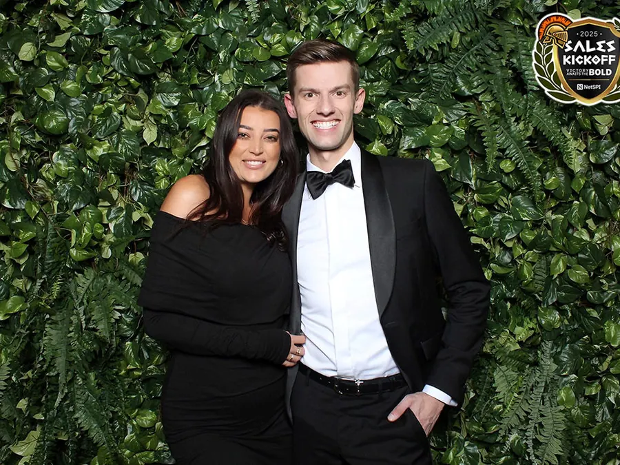 Couple posing in front of a hedge wall photo booth backdrop